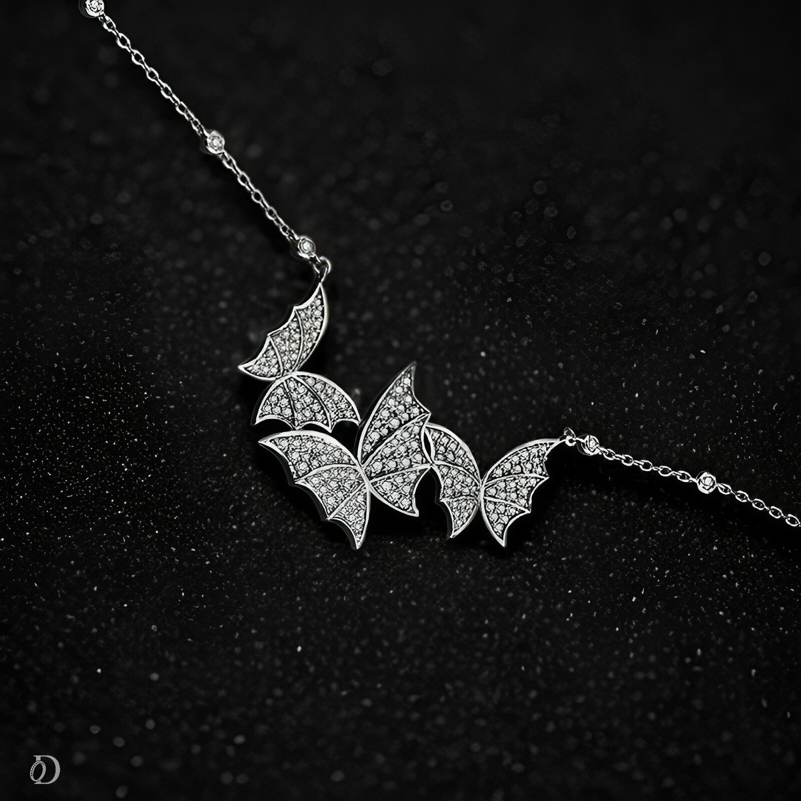 Silver butter fly-shaped necklace on a black textured background