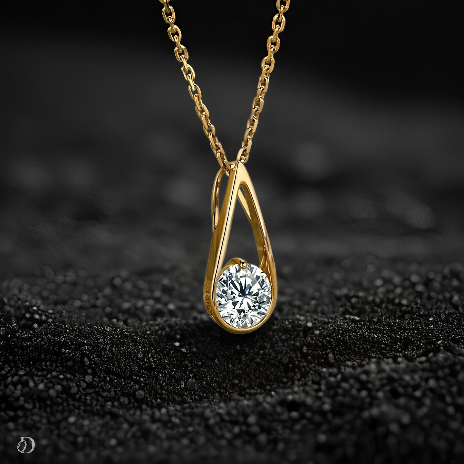 Gold necklace with a diamond pendant on a black textured surface