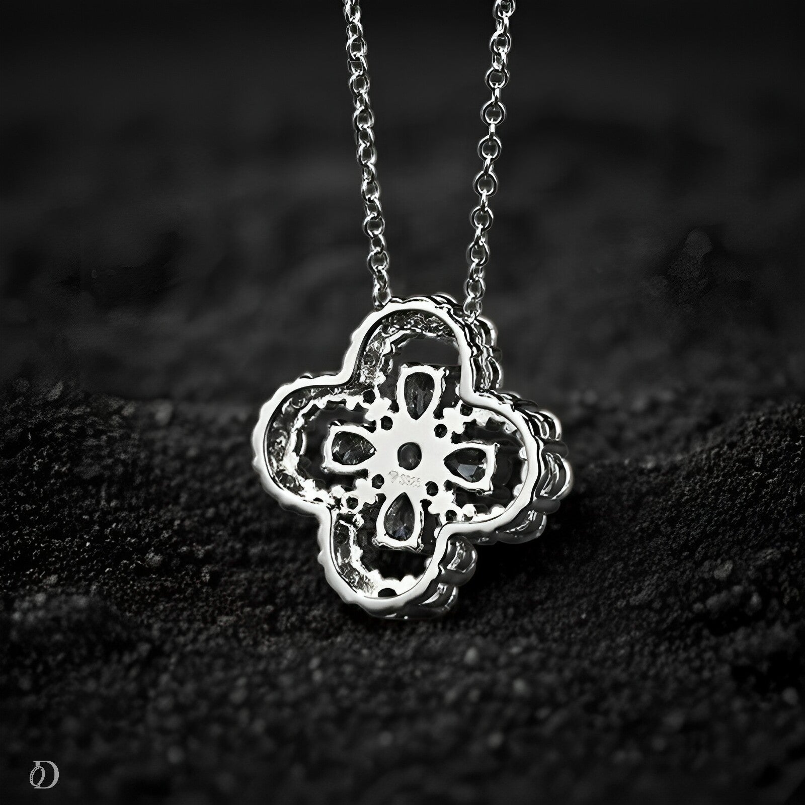 Silver necklace with a detailed pendant on a dark textured surface
