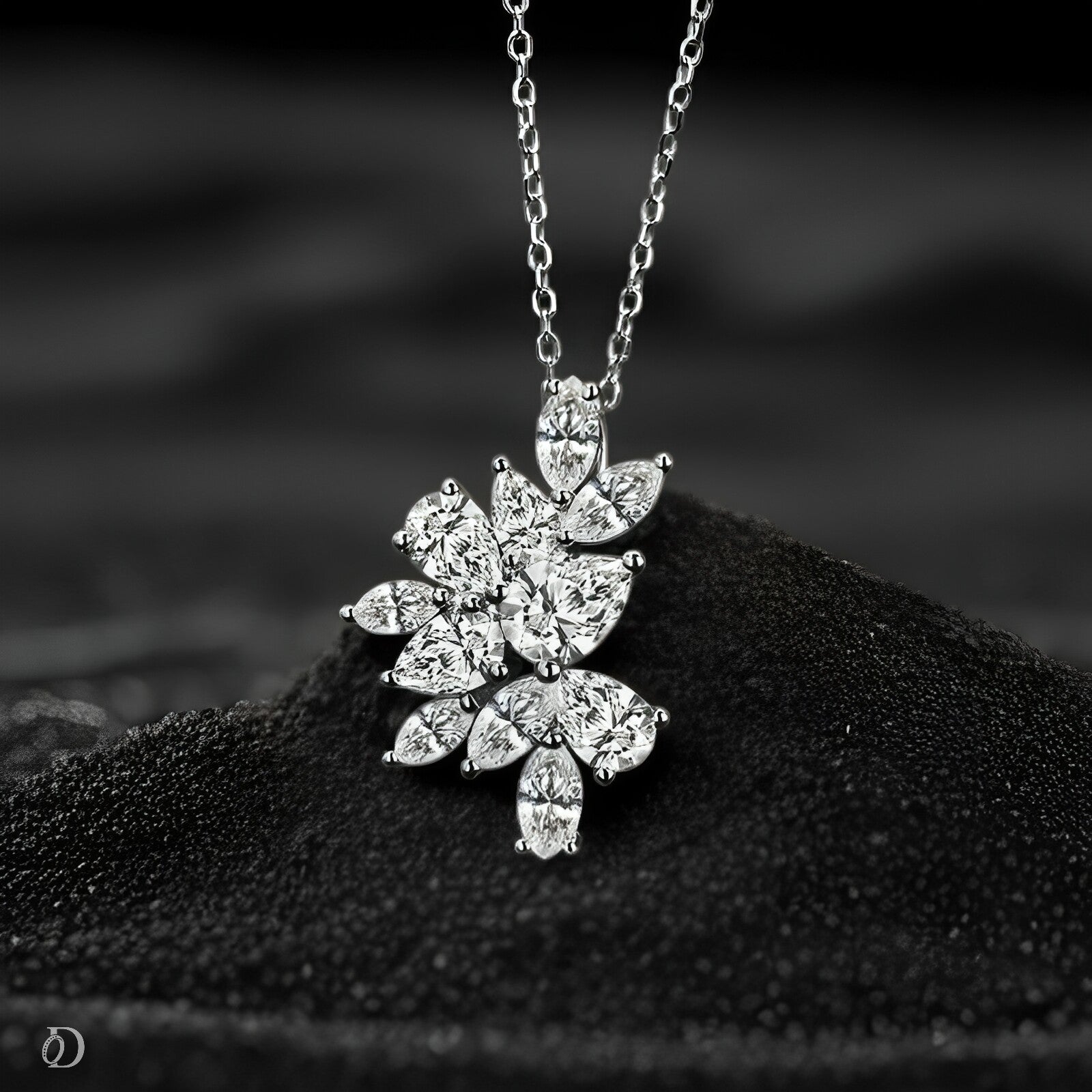 Silver leaf-shaped pendant necklace on a textured black surface with a blurred background