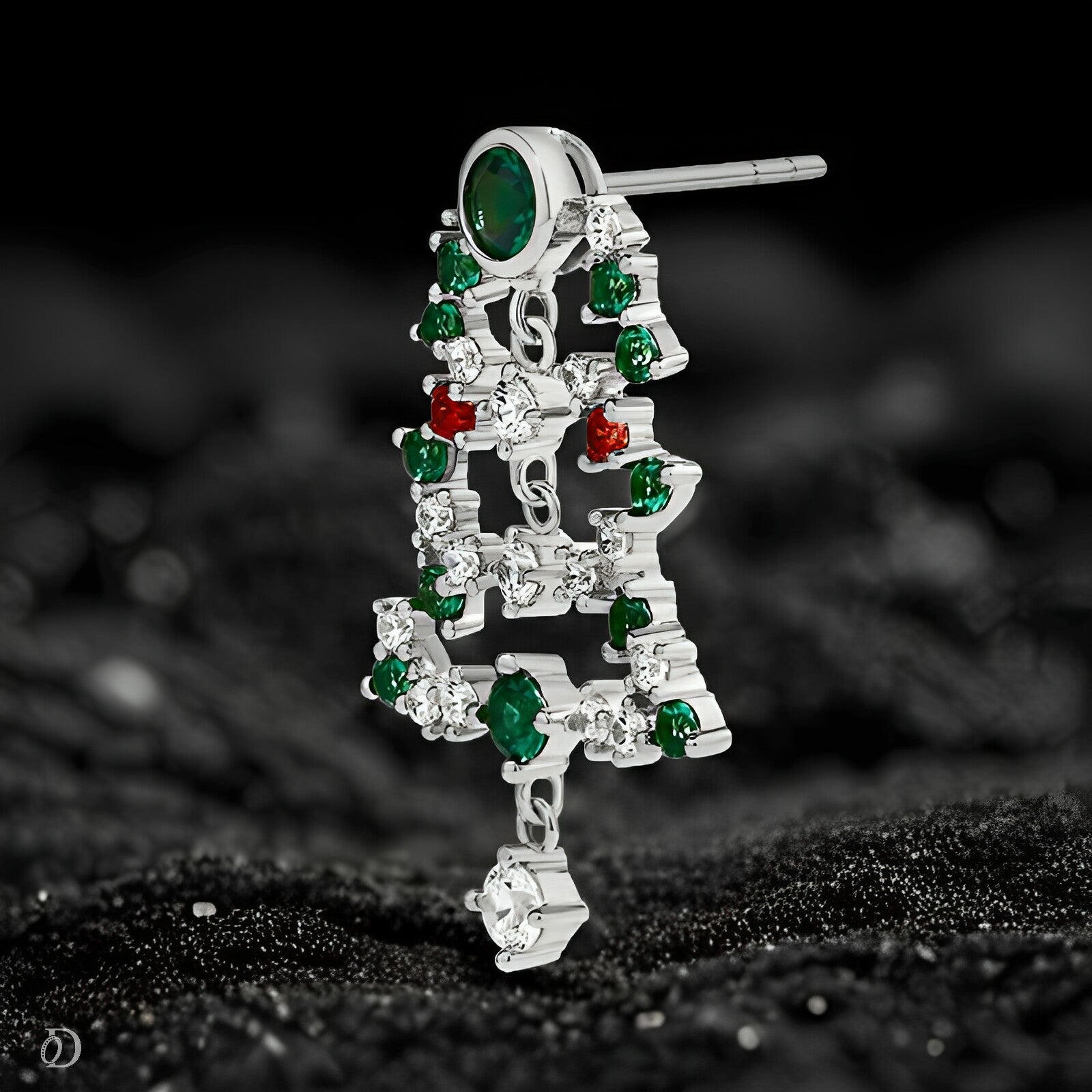 Silver earring with green and red gemstones on a black background