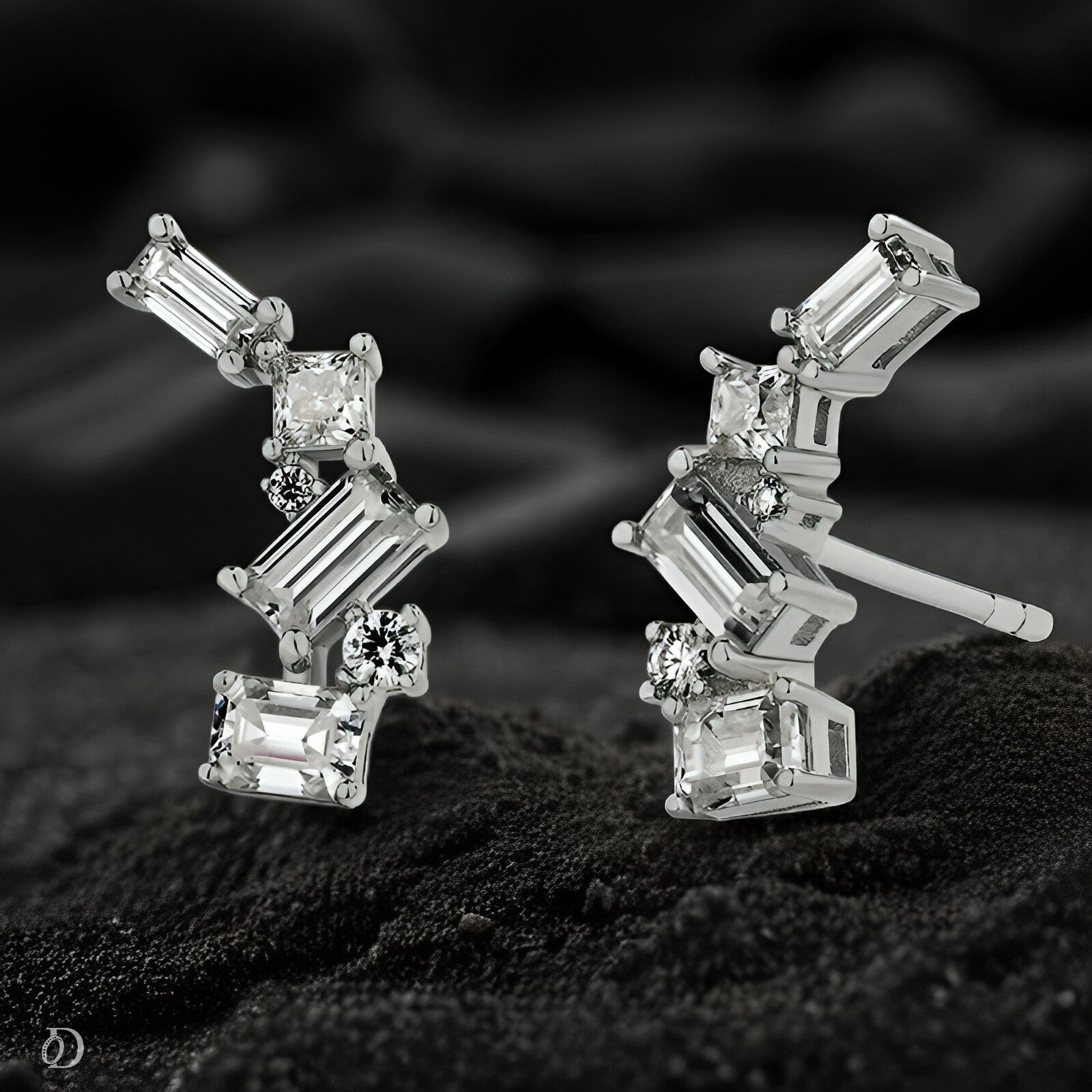 Pair of diamond earrings on a dark textured surface with a blurred background