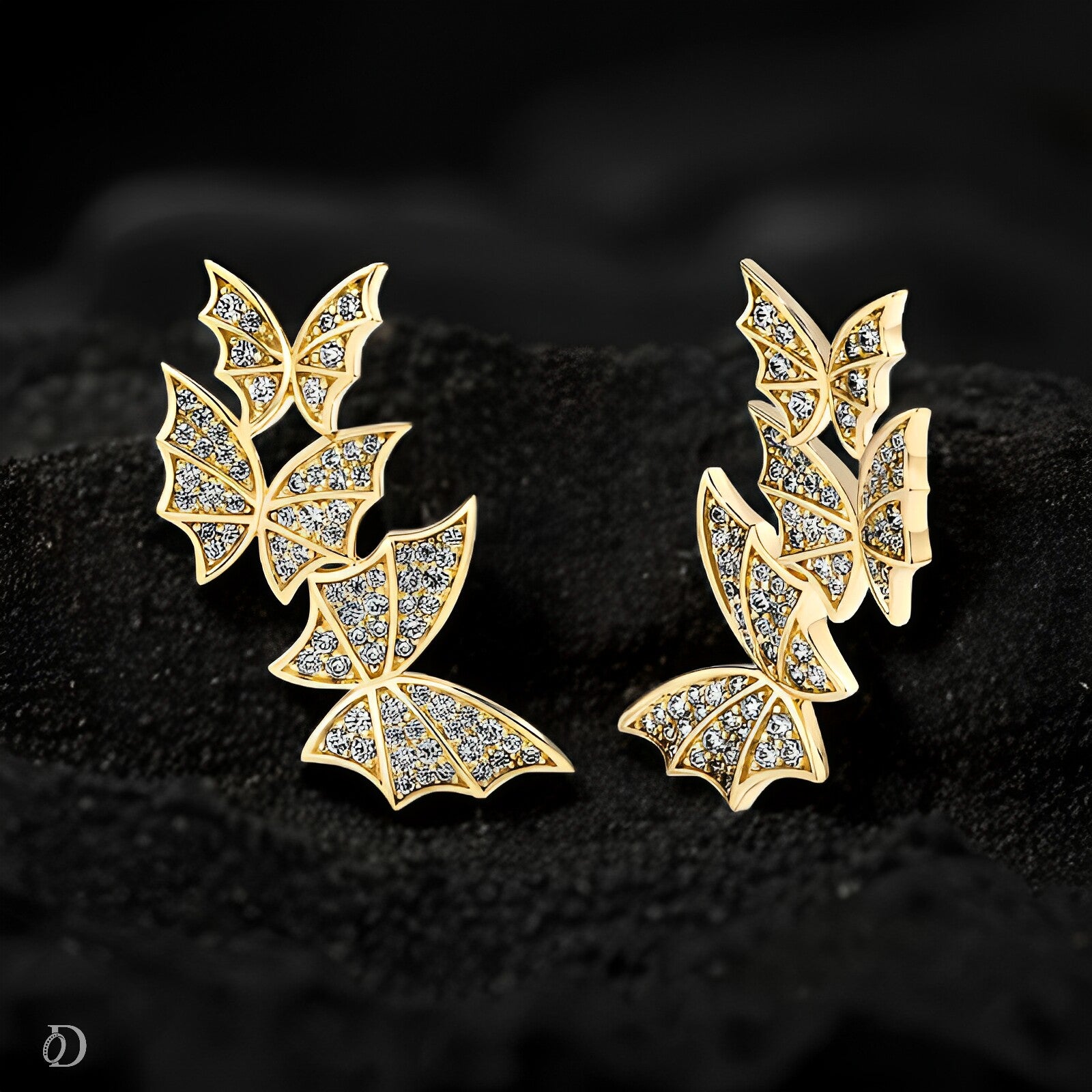 Gold butterfly earrings with gemstones on a black textured background
