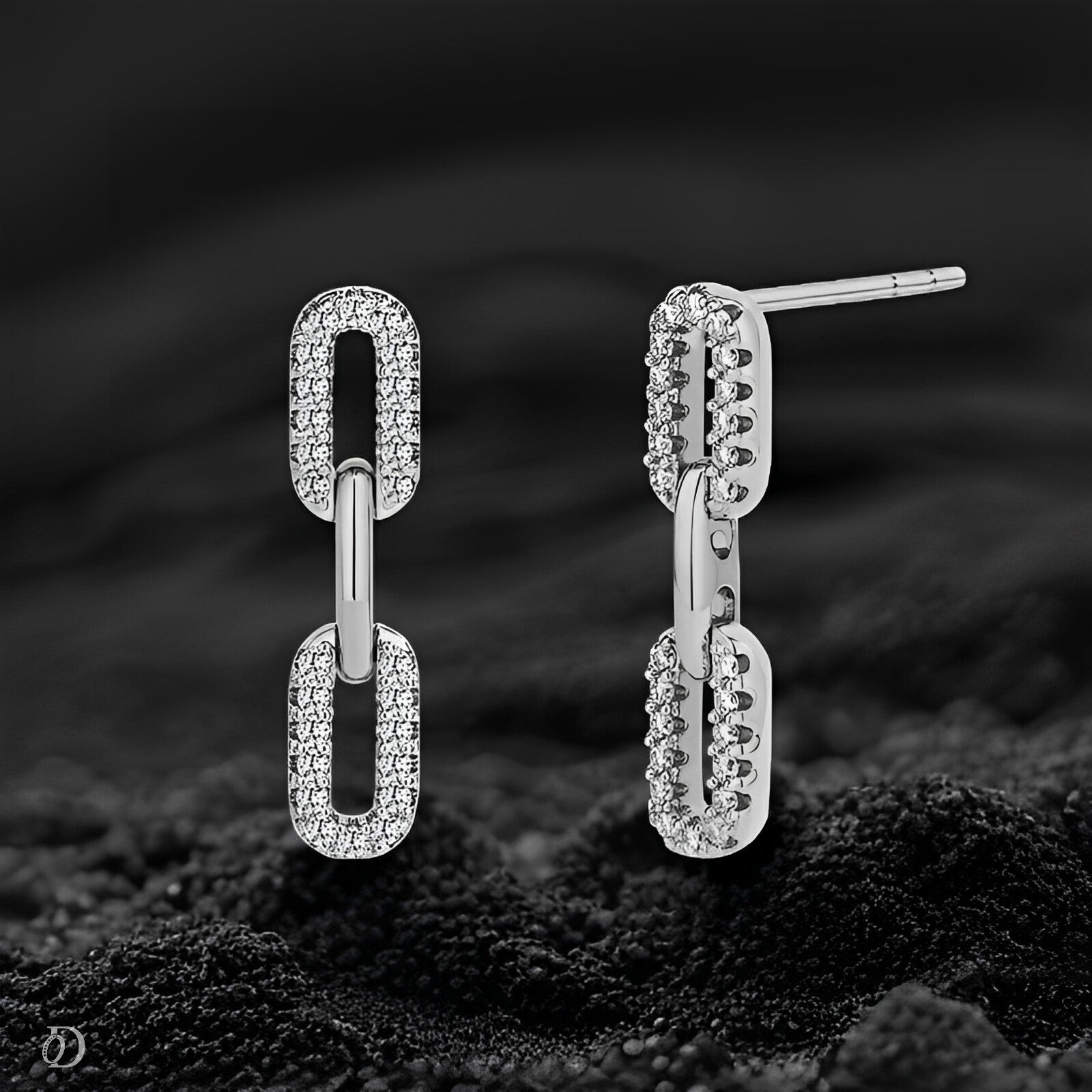 Pair of silver chain-link earrings on a dark textured surface