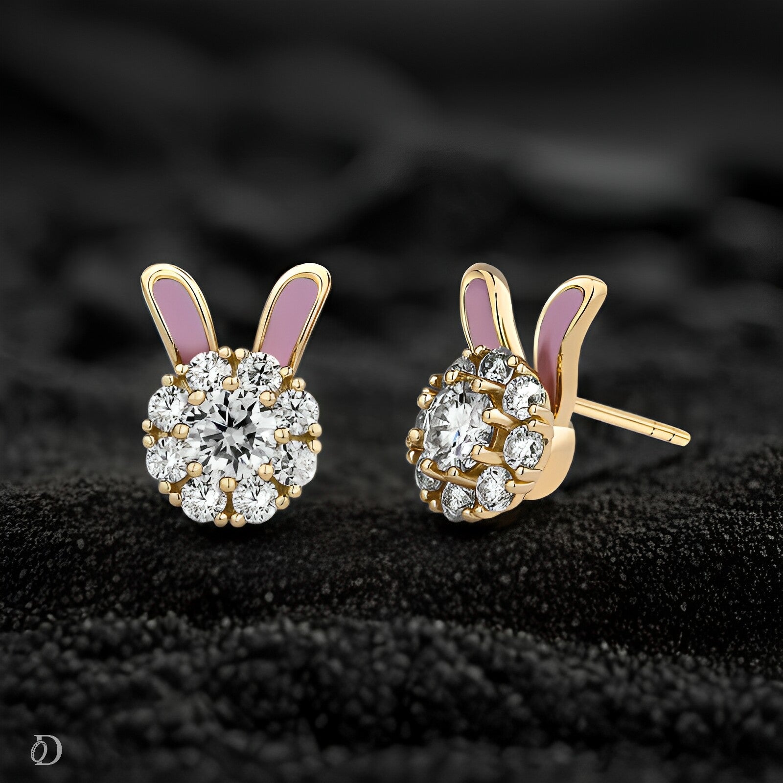Gold bunny-shaped earrings with diamond-like stones on a black textured background