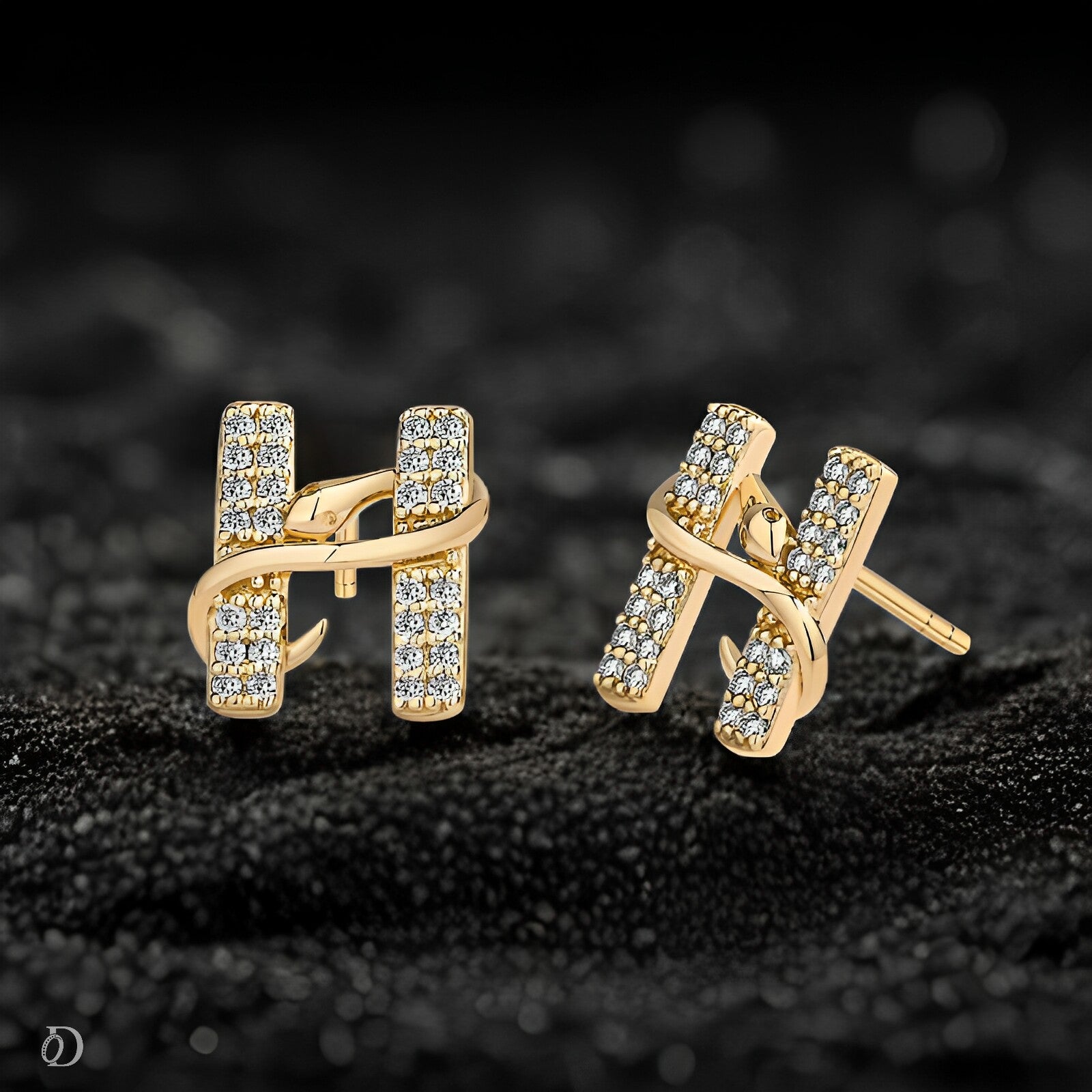 Gold earrings with diamond accents on a black textured background