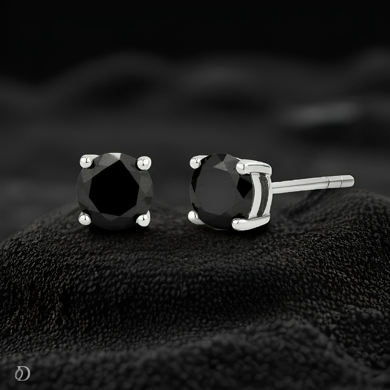 Black gemstone stud earrings on a textured black surface with a blurred dark background