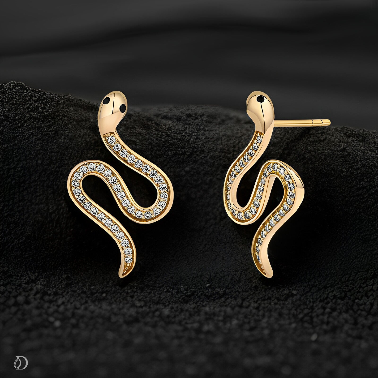 Gold snake-shaped earrings with diamond accents on a black textured background