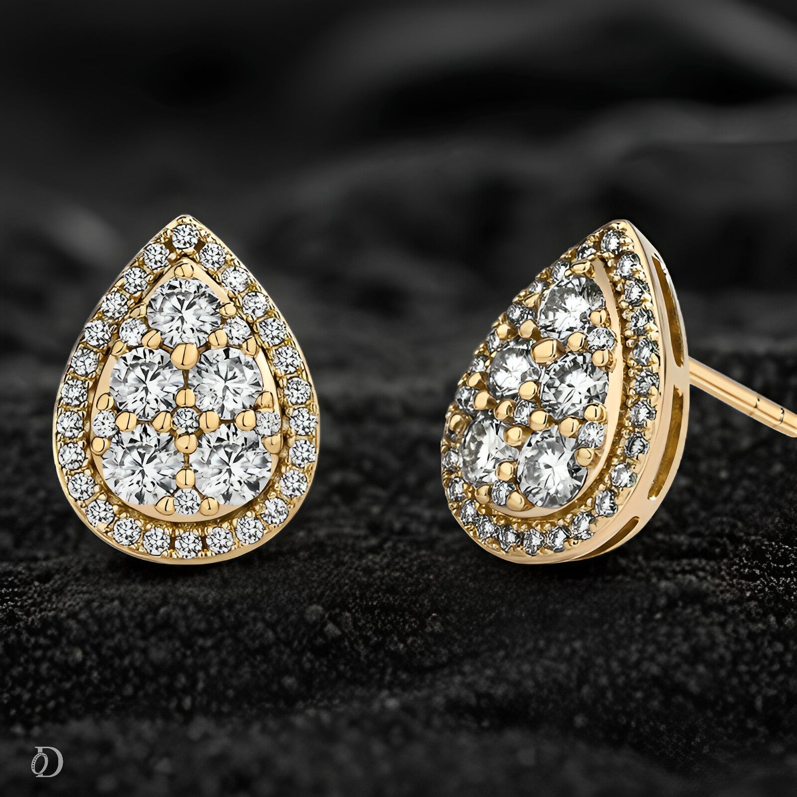 Gold teardrop earrings with clear gemstones on a dark textured background