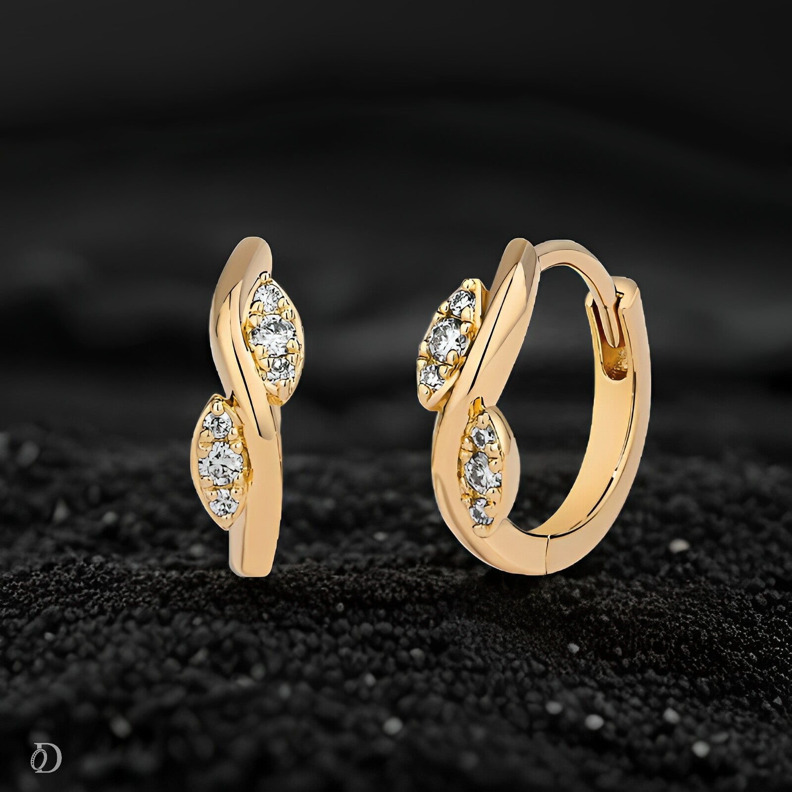 Gold hoop earrings with diamond accents on a black textured background