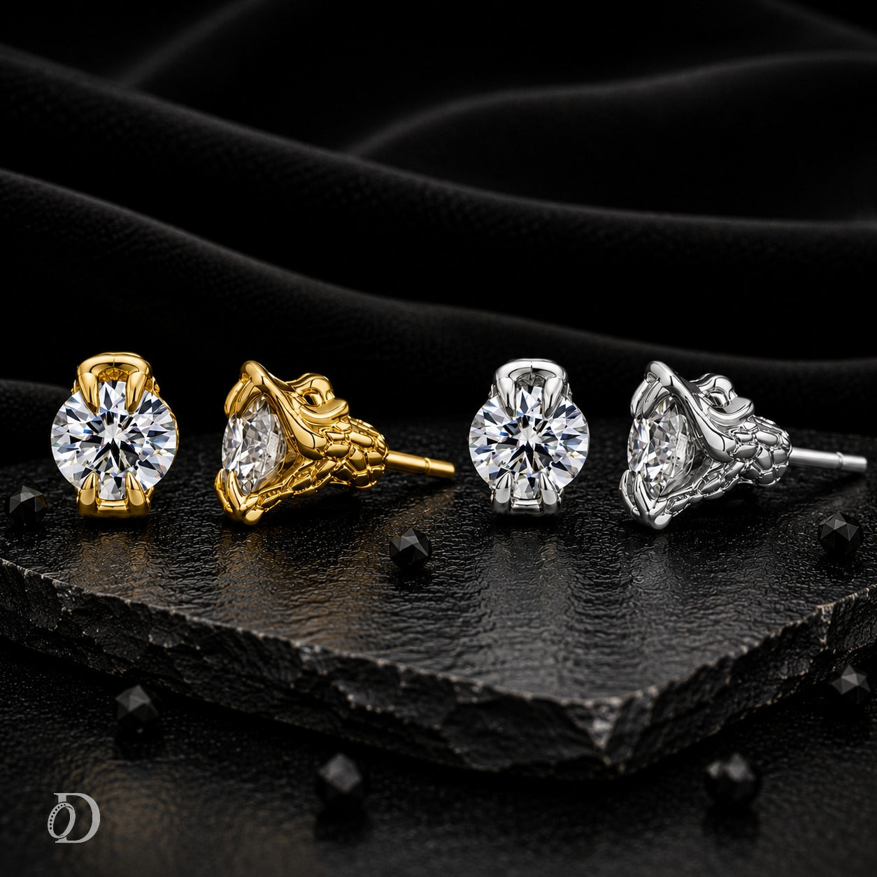 Four stud earrings displayed on a dark textured surface with draped black fabric behind them. Two earrings are gold-toned with round clear stones, and two are silver-toned with round clear stones.