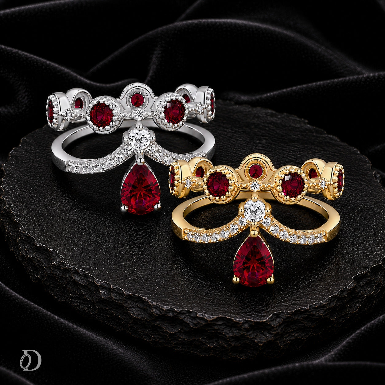 Two ornate rings displayed on a black fabric surface. One ring is silver-toned with red gemstones and clear stones, and the other is gold-toned with matching red gemstones and clear stones.