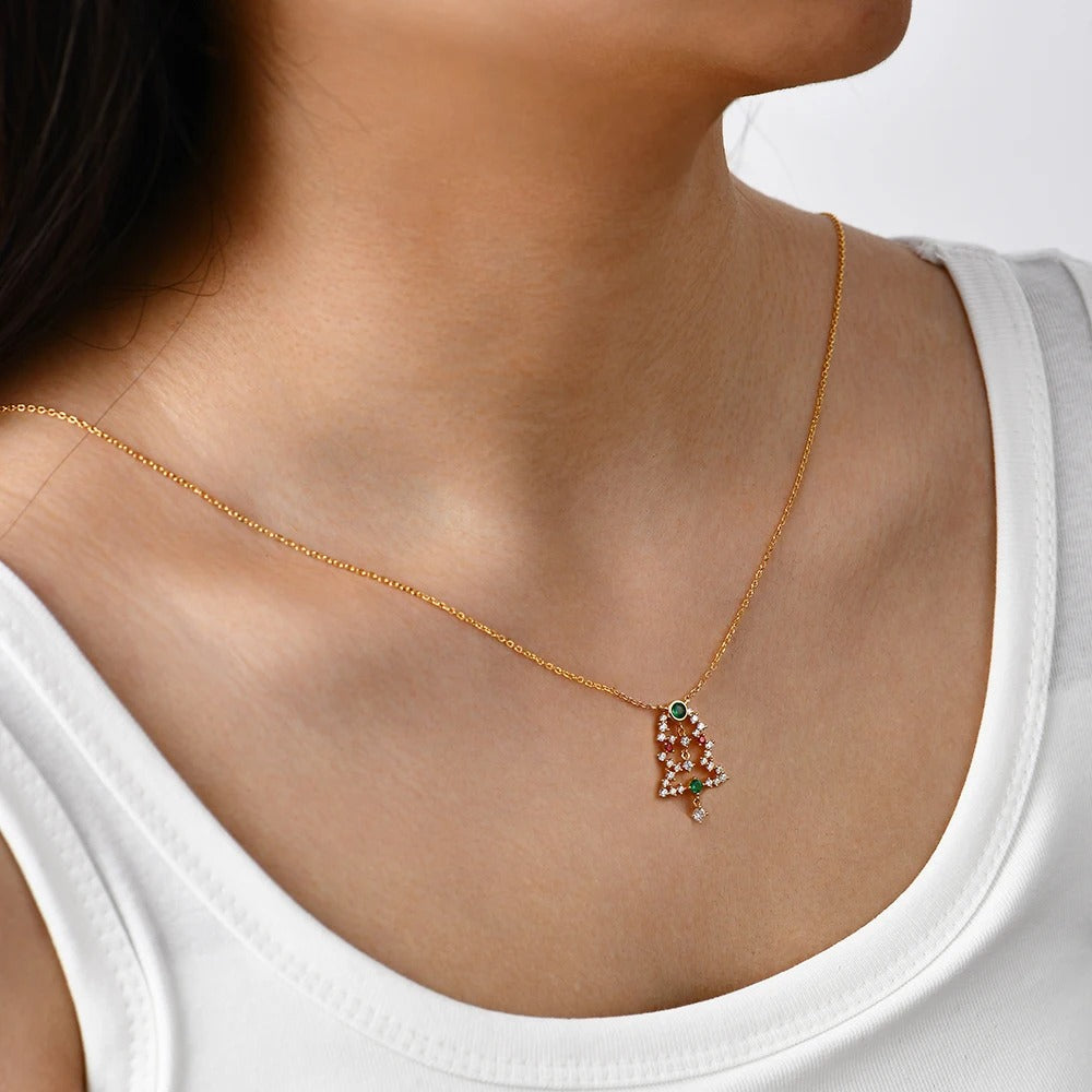 Gold necklace with a pendant worn by a person in a white tank top.