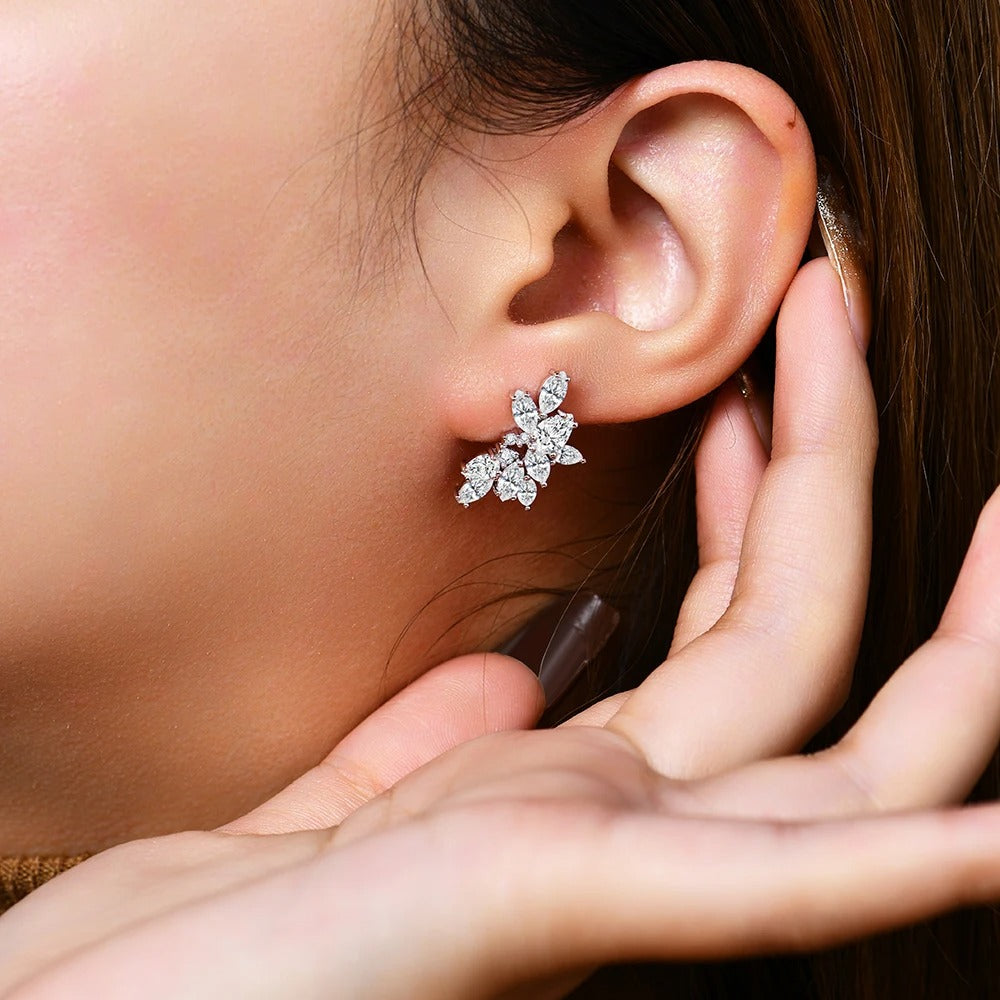 Close-up of a person wearing a silver floral earring with a hand adjusting it.