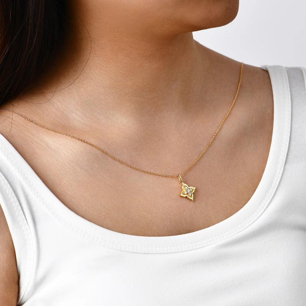 Gold necklace with a star-shaped pendant worn by a person in a white tank top.