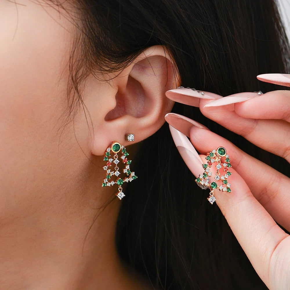 Close-up of an ear wearing a decorative earring with a hand holding another similar earring.