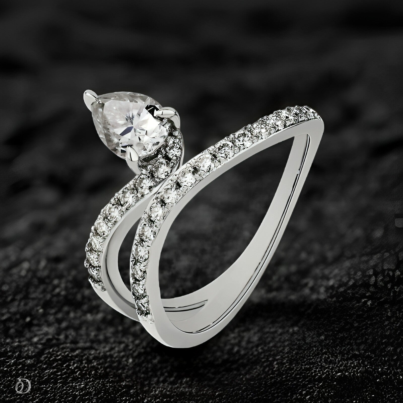 Silver ring with a pear-shaped diamond on a dark textured background