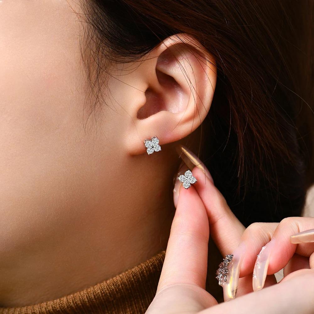 Close-up of a person wearing flower-shaped earrings with a blurred background