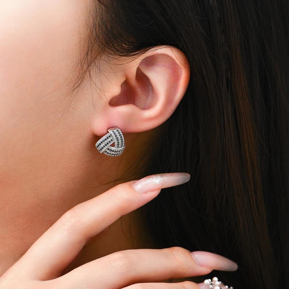 Close-up of an ear wearing a silver earring with a blurred background