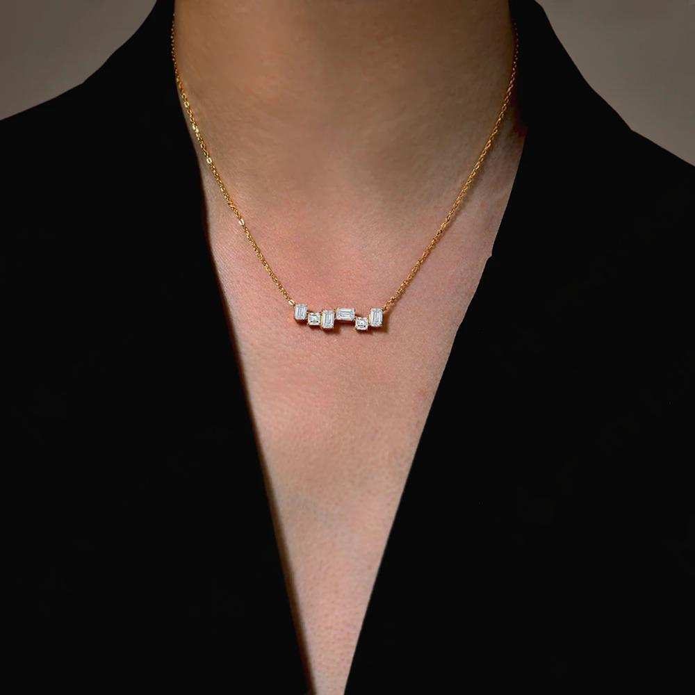 Gold necklace with small diamonds on a person wearing a black top.